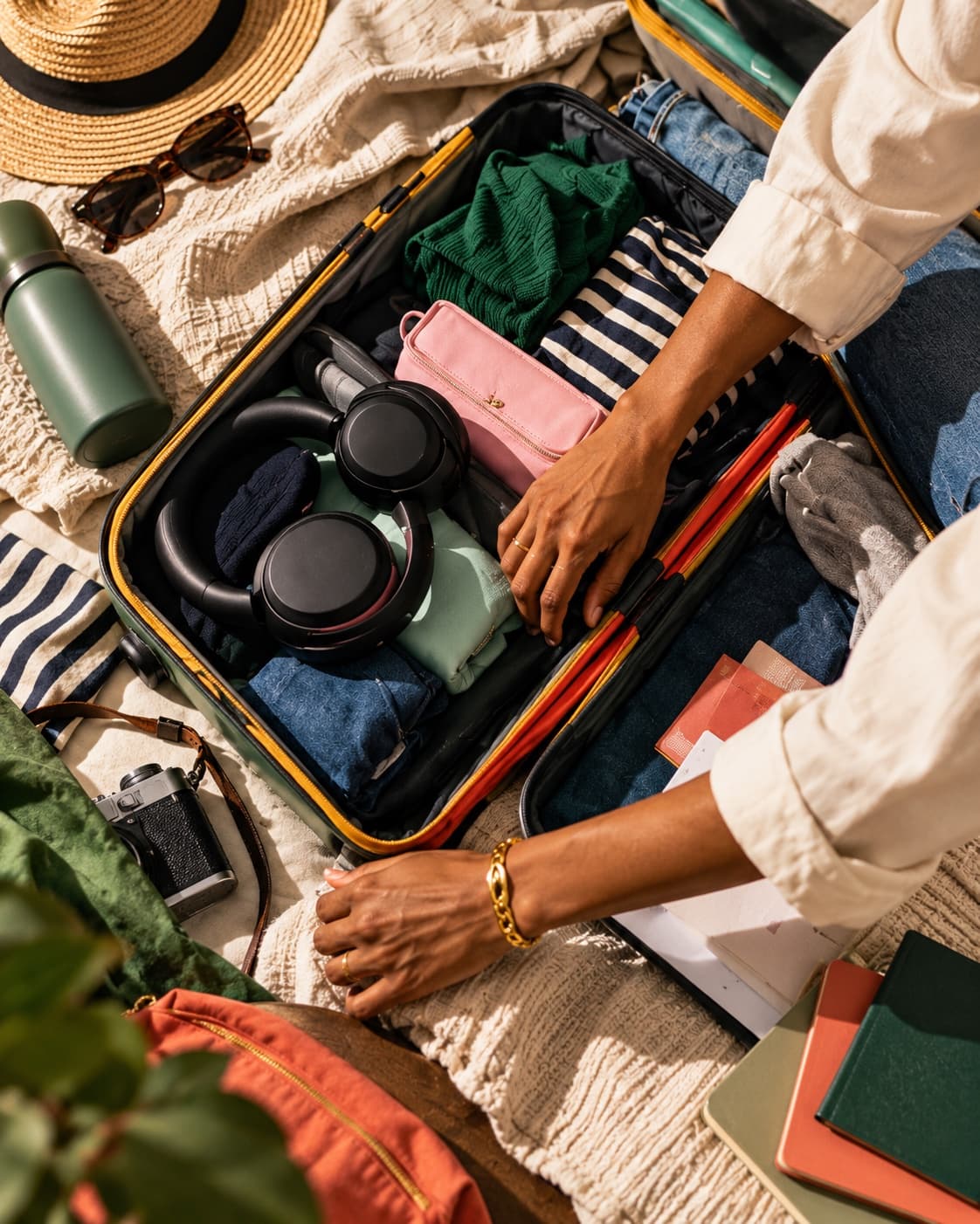 An open suitcase being packed with clothes and travel things.