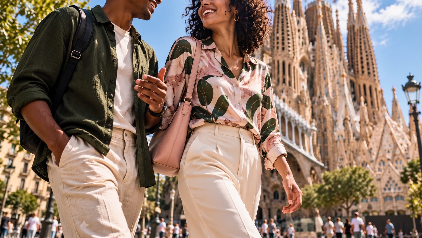 A couple walking and laughing in front of the Sagrada Família in Barcelona.